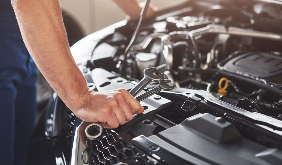 Picture showing muscular car service worker repairing vehicle.